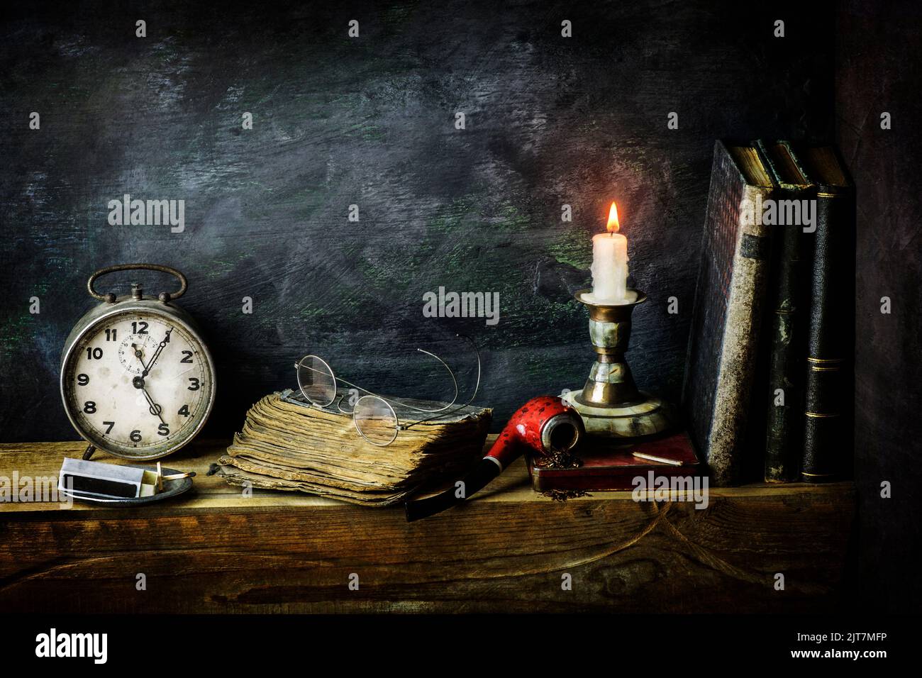 Vita morta classica con libri vintage collocati con vecchio orologio, pipa, bicchieri e candela illuminata su sfondo rustico in legno. Foto Stock
