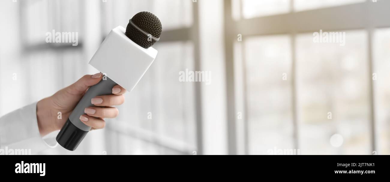 Giornalista femminile con microfono all'interno Foto Stock