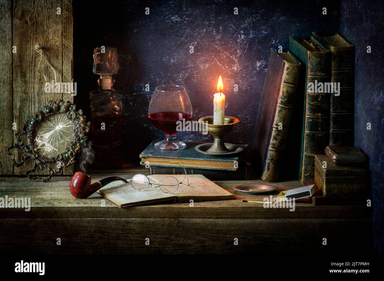 Still life classico con libri d'epoca collocati con vecchie scatole, spezzata cornice, tubo, vetri antichi, candela illuminata, bottiglia e bicchiere di vino rosso. Foto Stock