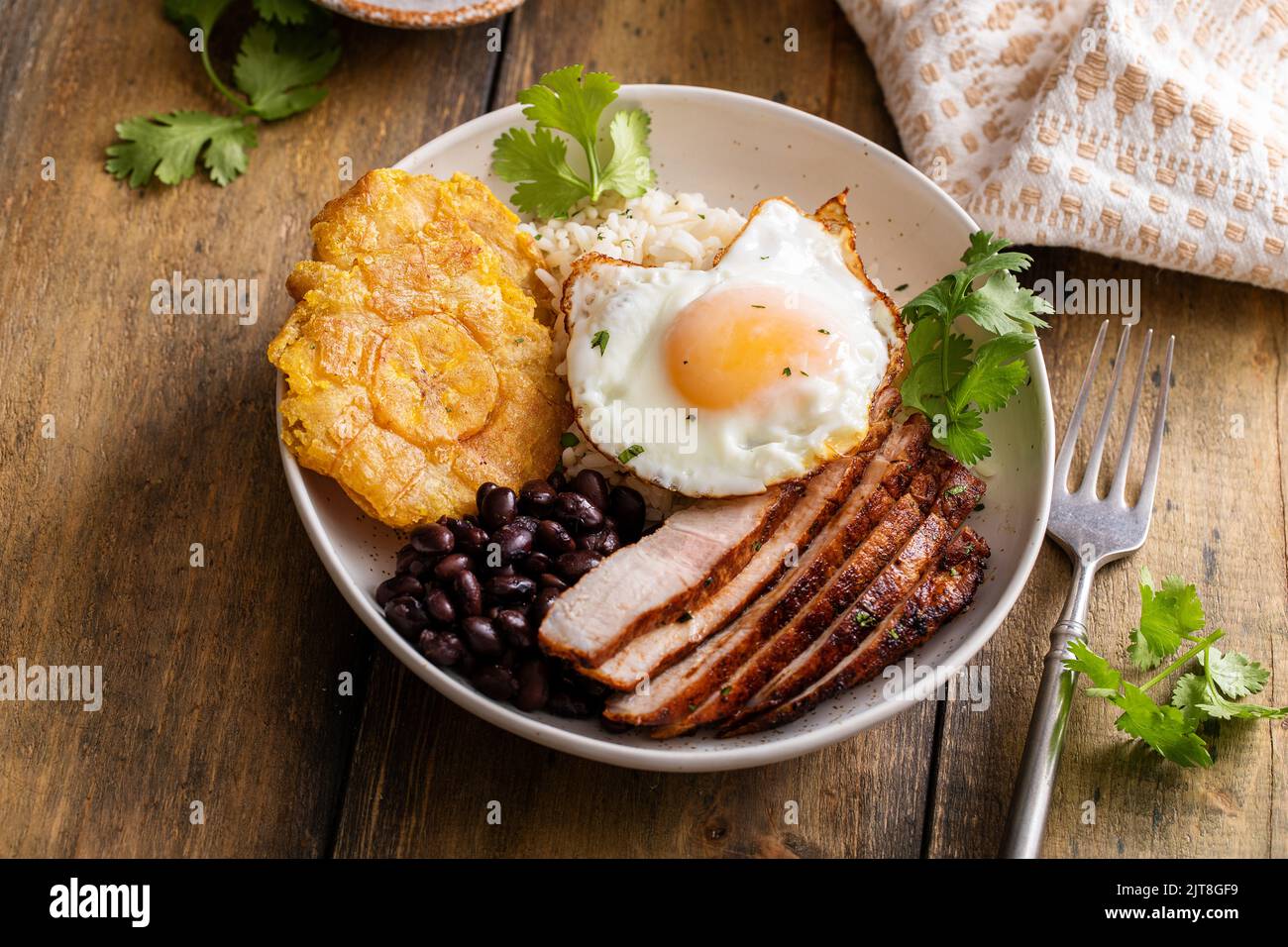 Colazione caraibica o latinoamericana con riso, fagioli, noccioli e maiale affettato condito con uova fritte Foto Stock