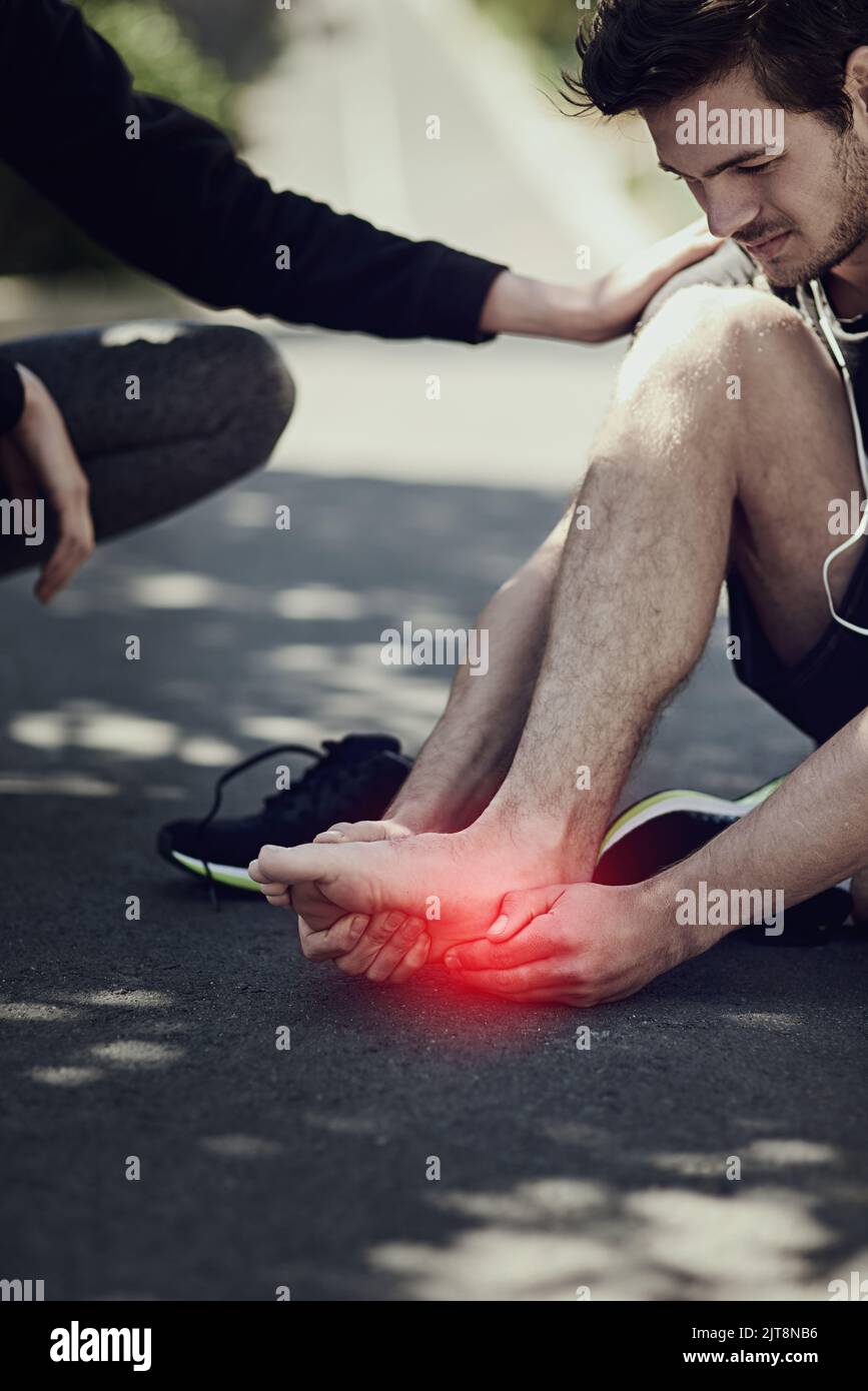 I rischi della corsa. Un giovane che soffre con il crampo del piede durante una corsa. Foto Stock