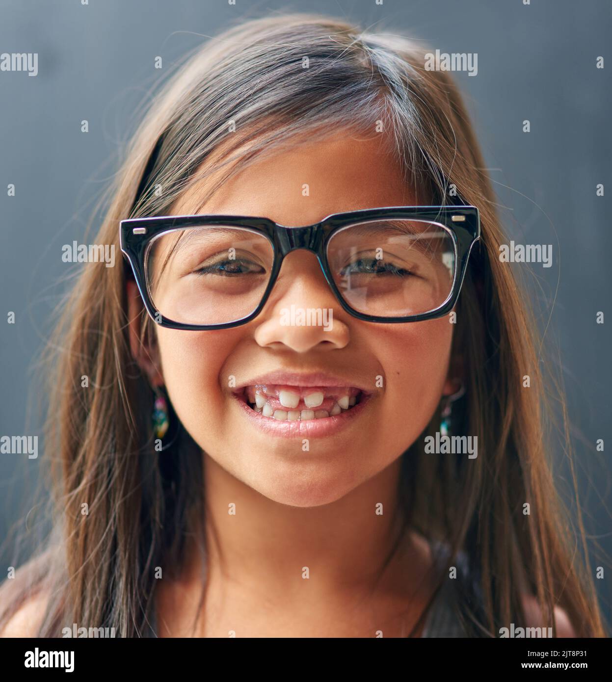 La gioia di essere un bambino. Studio ritratto di una bambina che indossa occhiali su uno sfondo scuro. Foto Stock