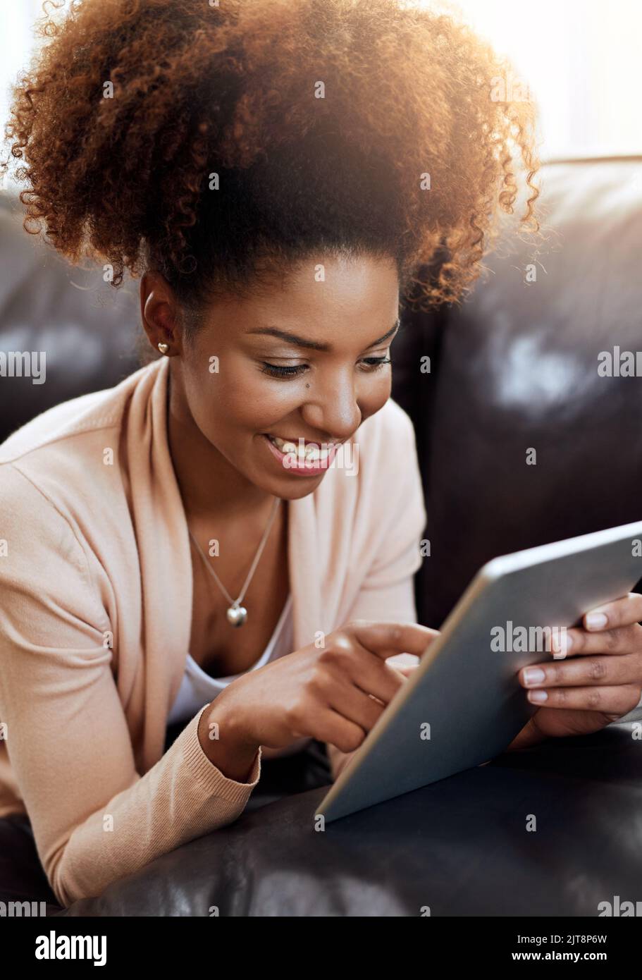 Tutto l'intrattenimento del weekend in un unico dispositivo. Una giovane donna rilassata che usa un tablet digitale sul divano di casa. Foto Stock