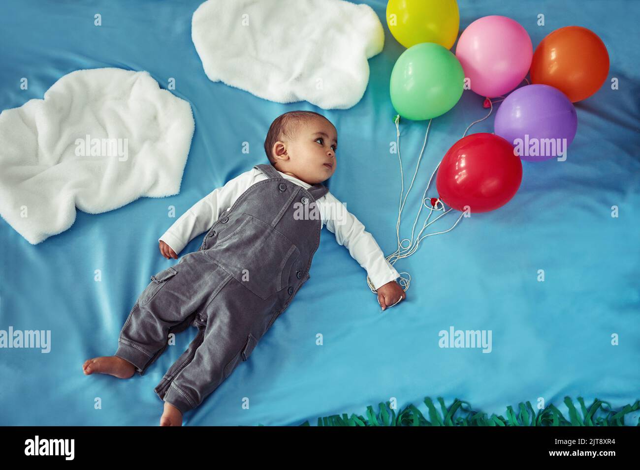 Da qui in poi, il skys il limite. Concept shot di un adorabile bambino che vola attraverso il cielo tenendo un mazzo di palloncini. Foto Stock