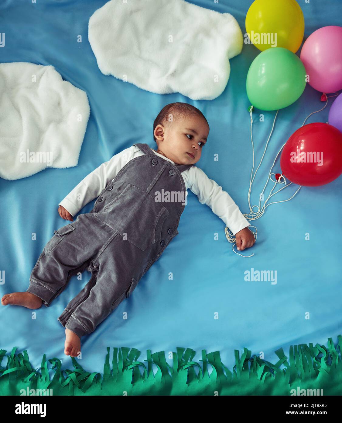 Su, su e via. Concept shot di un adorabile bambino che vola attraverso il cielo tenendo un mazzo di palloncini. Foto Stock