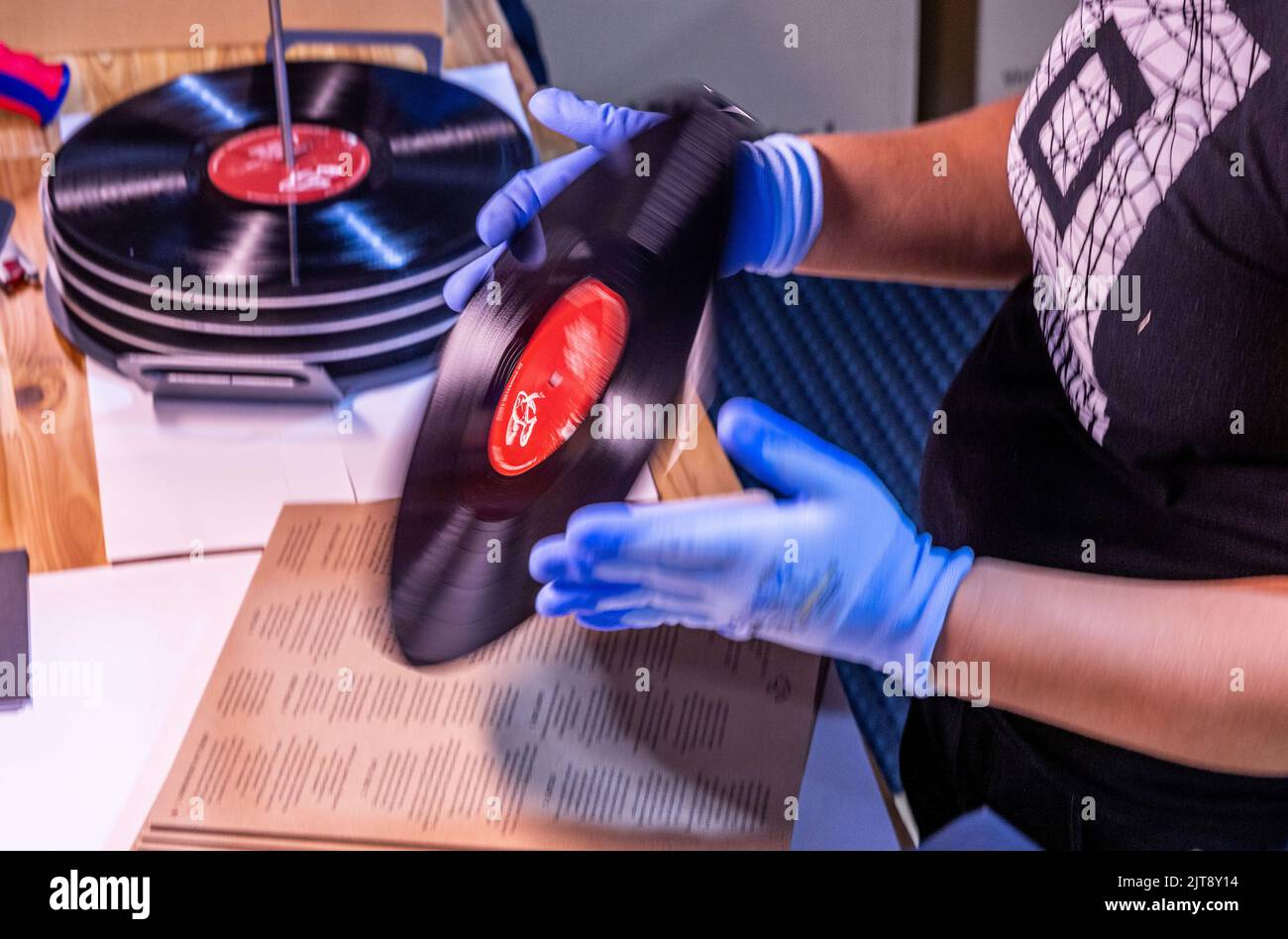 22 agosto 2022, Meclemburgo-Pomerania occidentale, Güstrow: I dipendenti della società discografica 'questione di fatto' controllano e imballano i record appena pressati nelle loro copertine. (L'azienda, che attualmente impiega cinque persone, produce record per diverse settimane in un ex locale per la patata, che ha dovuto essere ampiamente convertito per la produzione da record. Con una forza di 150 tonnellate, le lunghe registrazioni sono prodotte da cloruro di polivinile (PVC) sulle presse a 200 gradi Celsius. Ogni anno devono essere premuti tra 250.000 e 300.000 record. Secondo l'Associazione tedesca dell'industria musicale, Foto Stock