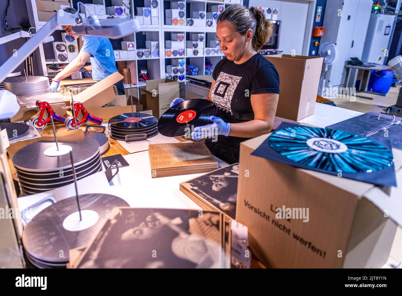 22 agosto 2022, Meclemburgo-Pomerania occidentale, Güstrow: I dipendenti della società discografica 'questione di fatto' controllano e imballano i record appena pressati nelle loro copertine. L'azienda, che attualmente ha cinque dipendenti, produce record per diverse settimane in un'ex sala patata che ha dovuto essere ampiamente convertito per la produzione di dischi. Con una forza di 150 tonnellate, i dischi di lunga durata sono prodotti sulle presse a 200 gradi Celsius da cloruro di polivinile (PVC). Ogni anno devono essere premuti tra 250.000 e 300.000 record. Secondo l'Associazione tedesca dell'industria musicale, ov Foto Stock