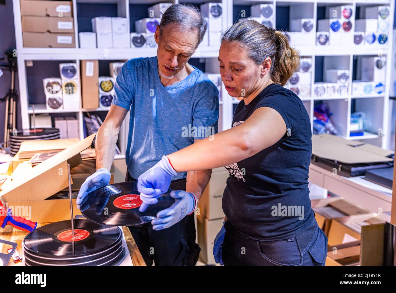 22 agosto 2022, Meclemburgo-Pomerania occidentale, Güstrow: I dipendenti della società discografica 'questione di fatto' controllano e imballano i record appena pressati nelle loro copertine. L'azienda, che attualmente ha cinque dipendenti, produce record per diverse settimane in un'ex sala patata che ha dovuto essere ampiamente convertito per la produzione di dischi. Con una forza di 150 tonnellate, i dischi di lunga durata sono prodotti sulle presse a 200 gradi Celsius da cloruro di polivinile (PVC). Ogni anno devono essere premuti tra 250.000 e 300.000 record. Secondo l'Associazione tedesca dell'industria musicale, ov Foto Stock
