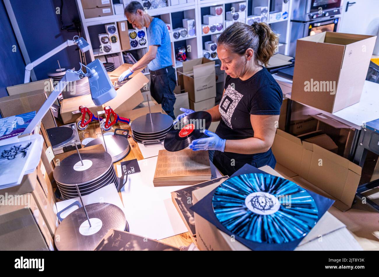 22 agosto 2022, Meclemburgo-Pomerania occidentale, Güstrow: I dipendenti della società discografica 'questione di fatto' controllano e imballano i record appena pressati nelle loro copertine. L'azienda, che attualmente ha cinque dipendenti, produce record per diverse settimane in un'ex sala patata che ha dovuto essere ampiamente convertito per la produzione di dischi. Con una forza di 150 tonnellate, i dischi di lunga durata sono prodotti sulle presse a 200 gradi Celsius da cloruro di polivinile (PVC). Ogni anno devono essere premuti tra 250.000 e 300.000 record. Secondo l'Associazione tedesca dell'industria musicale, ov Foto Stock