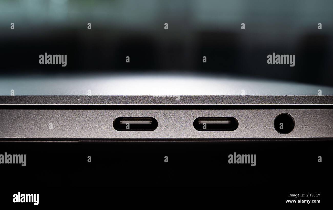 Pannello laterale di un notebook sottile con connettori USB Type-C per la ricarica e il trasferimento di file e un mini-jack da 3,5 mm per il collegamento di cuffie e altoparlanti Foto Stock