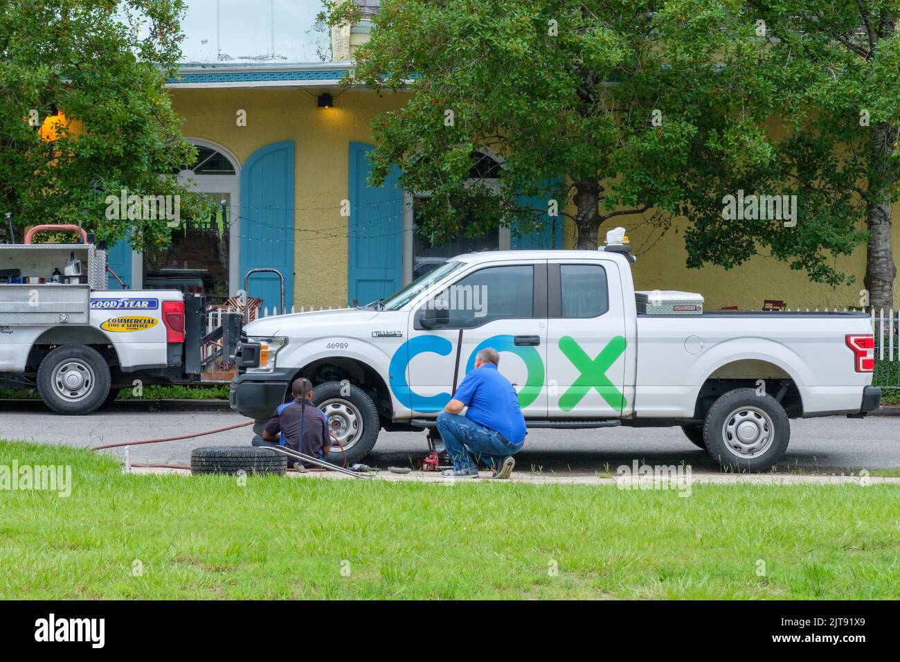 NEW ORLEANS, LA, USA - 24 AGOSTO 2022: Riparatore da Goodyear Roadside Service cambia uno pneumatico su un camion Cox Cable mentre il lavoratore Cox guarda su Foto Stock