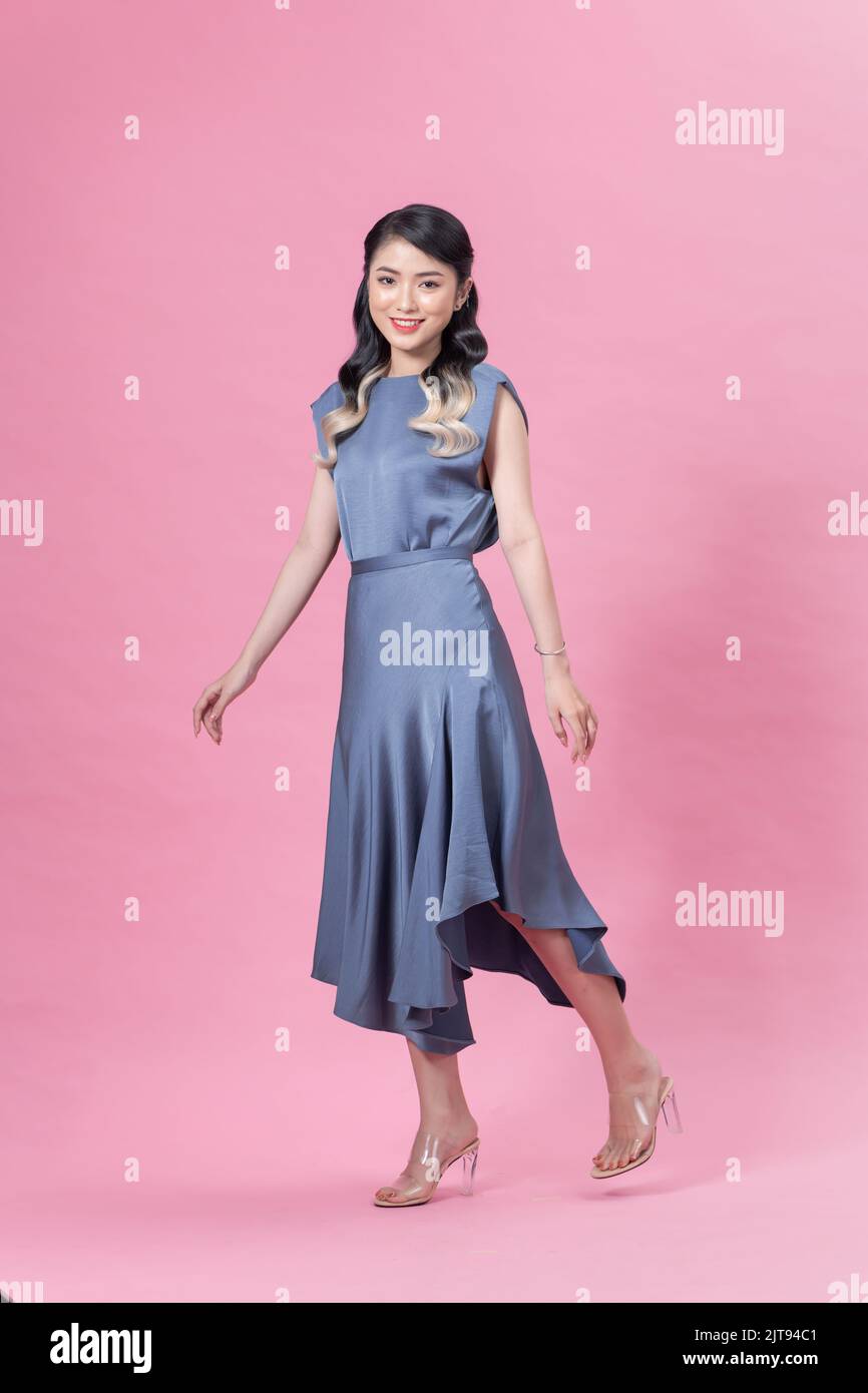Ritratto in piena crescita la giovane bella donna in un abito blu, isolato su sfondo rosa Foto Stock