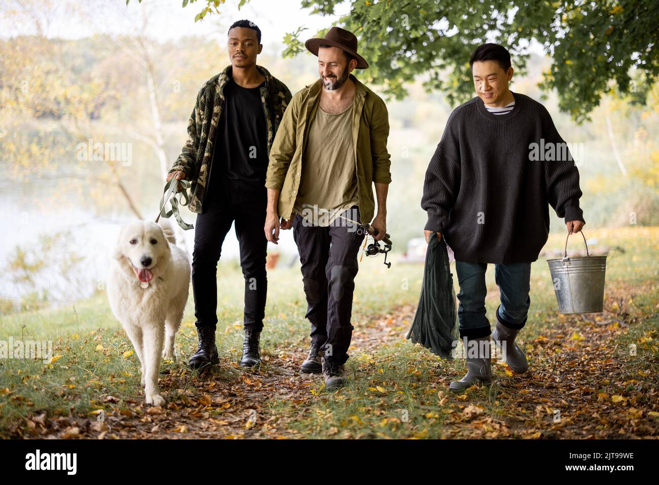 Gli uomini camminano con cane e attrezzatura da pesca in natura Foto Stock