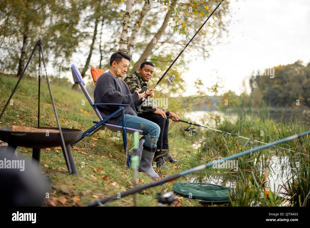 Uomo che parla con amici maschi a pesca in natura Foto Stock