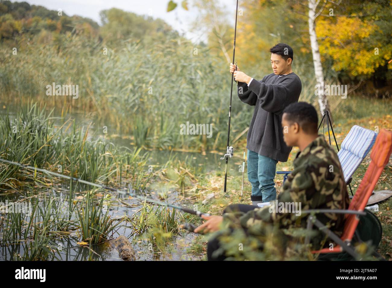 Uomo che parla con amici maschi a pesca in natura Foto Stock