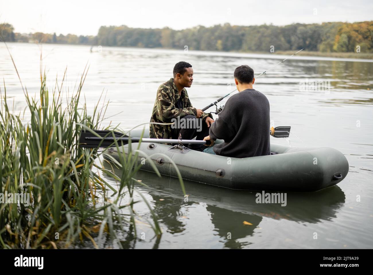 Amici maschi che pescano su gommone nel fiume Foto Stock