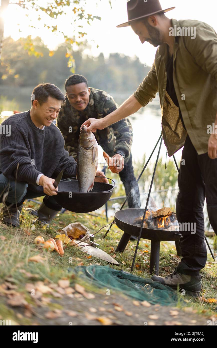 L'uomo ha messo il pesce grande in cavoldron per cucinare la zuppa di Ukha Foto Stock