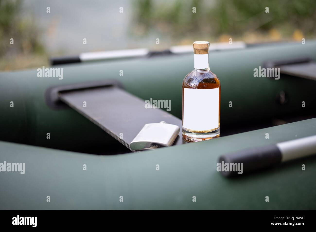 Bottiglia con alcol forte e matraccio su gommone Foto Stock