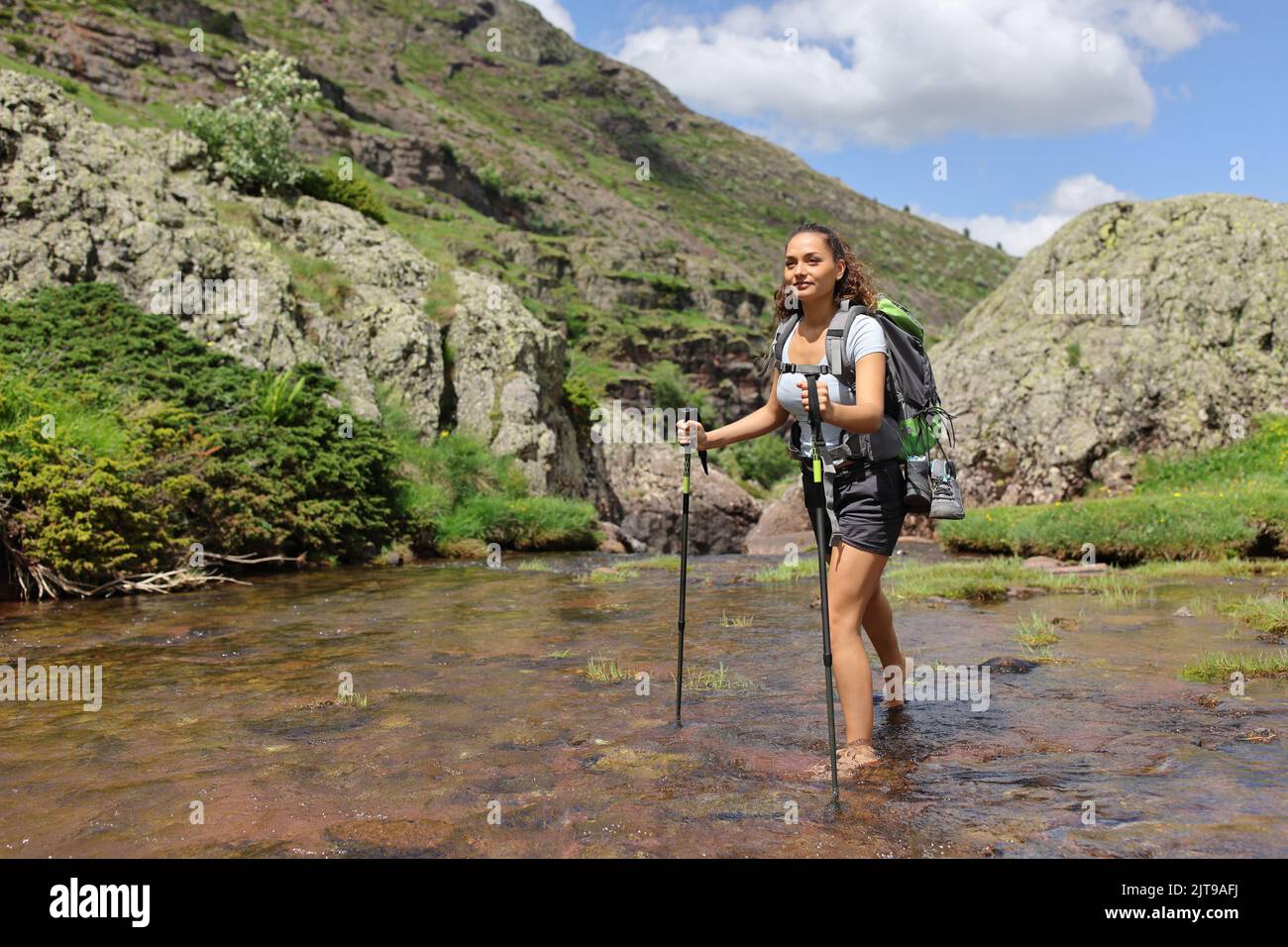 Buon barefoof escursionista che attraversa il fiume in montagna Foto Stock