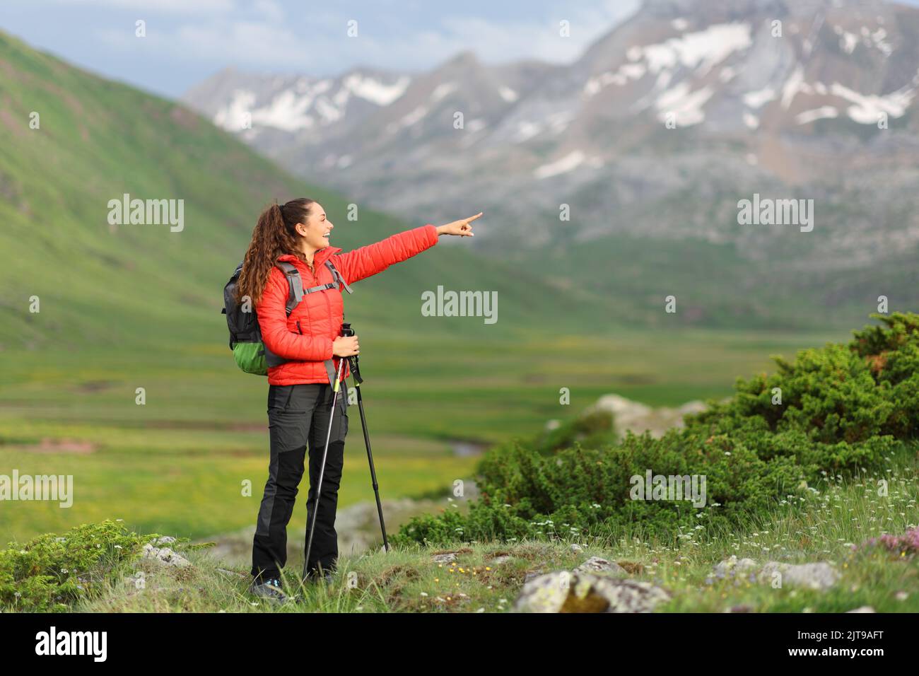 Felice escursionista in rosso che indica via in alta montagna Foto Stock
