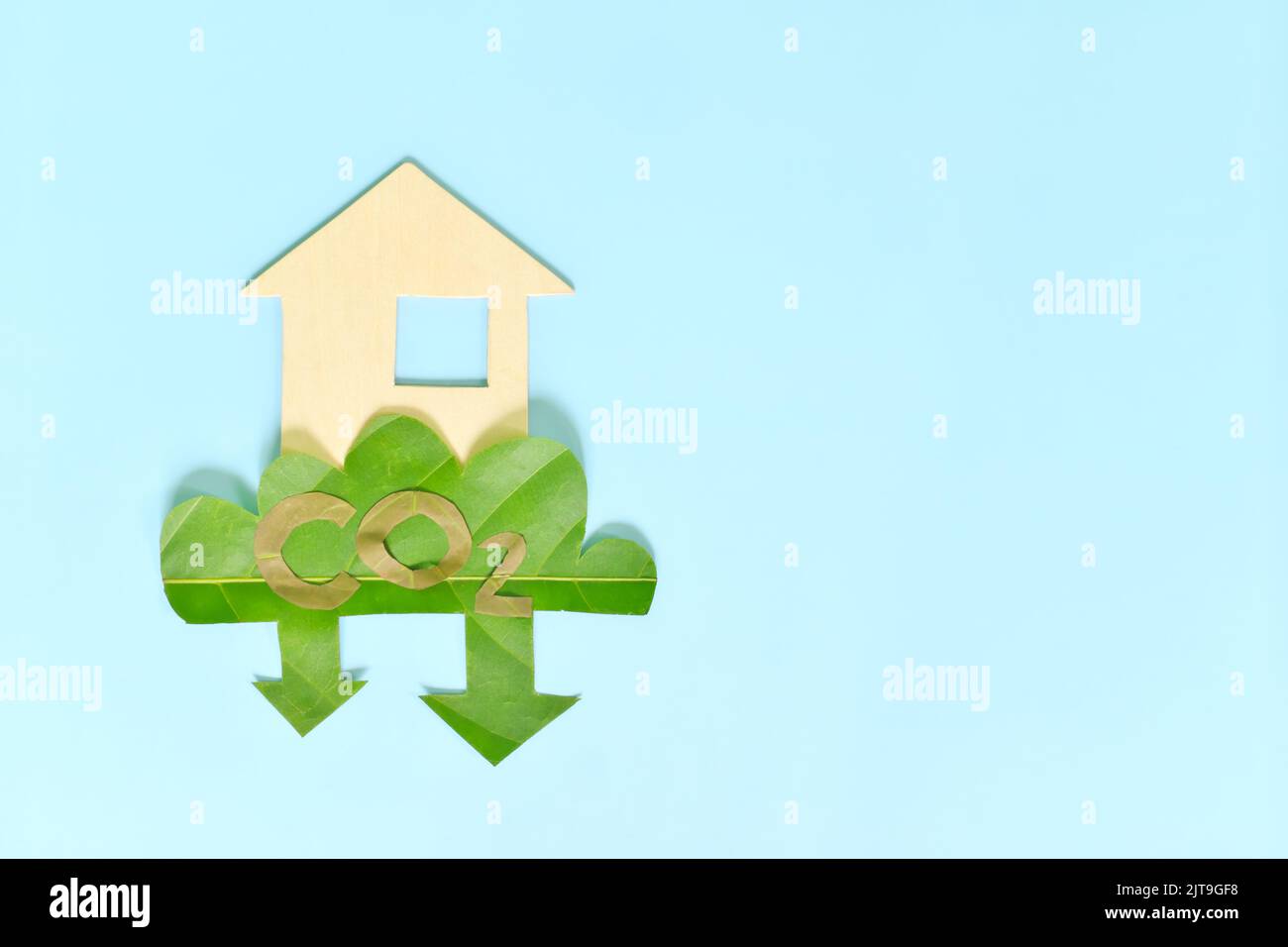 Riduzione delle emissioni di carbonio e concetto di vita sostenibile. Piatto composizione di CO2 foglia verde icona e casa ritagliata con spazio copia. Foto Stock