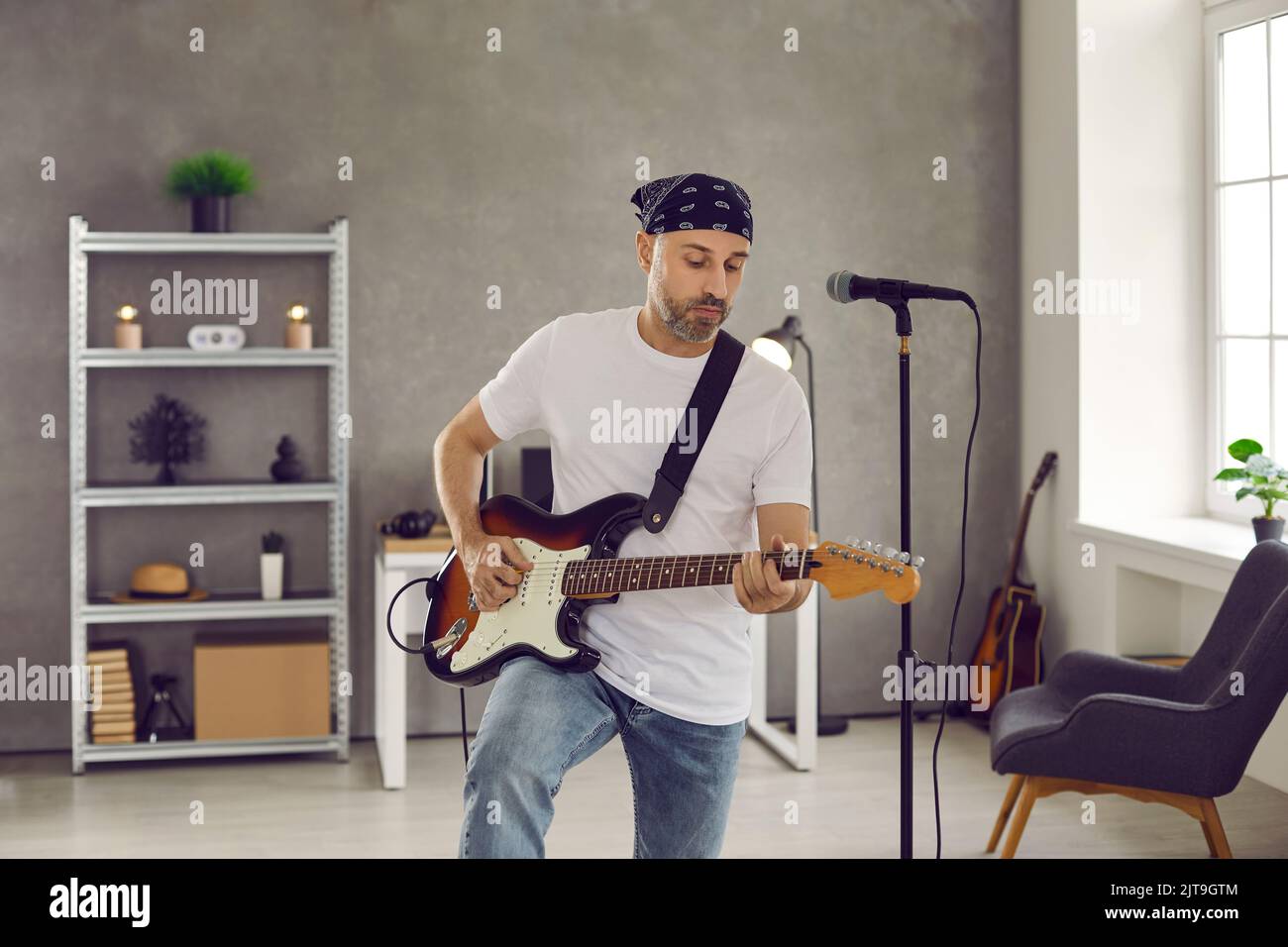 Musicista rock in piedi in sala prove e suonando musica sulla sua chitarra elettrica Foto Stock
