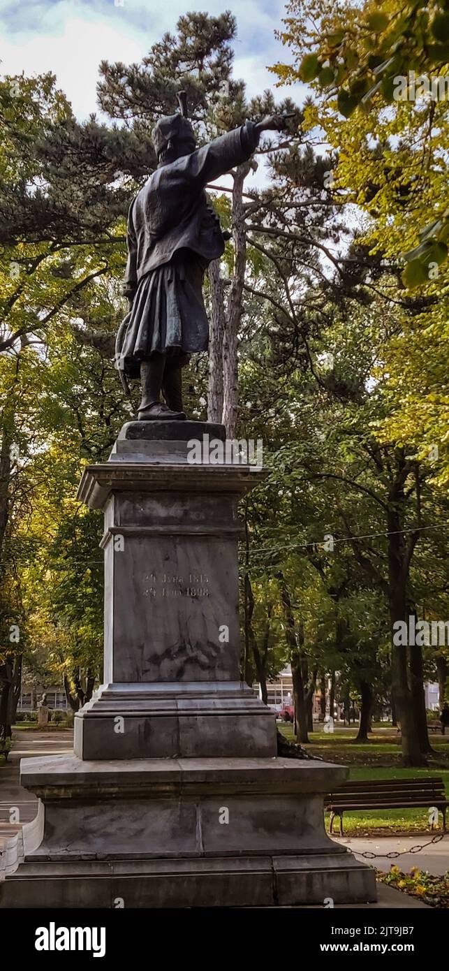 Uno scatto verticale di un monumento in un parco con alberi verdi sullo sfondo Foto Stock