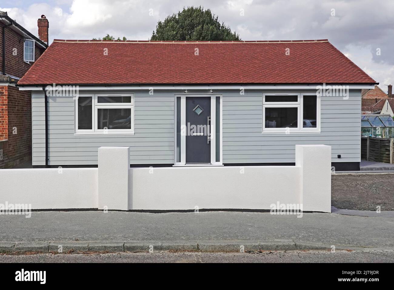 Fibra di cemento meteo imbarco sulla facciata di nuovo* grande area bungalow casa rosso tegola tetto parcheggio auto dietro la parete anteriore Inghilterra UK Foto Stock