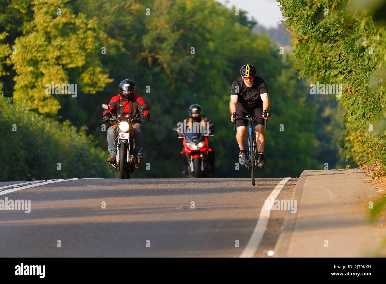 2 motociclisti sorpasso un ciclista ad una distanza di sicurezza sul fronte di una collina in Swillington, West Yorkshire, Regno Unito Foto Stock