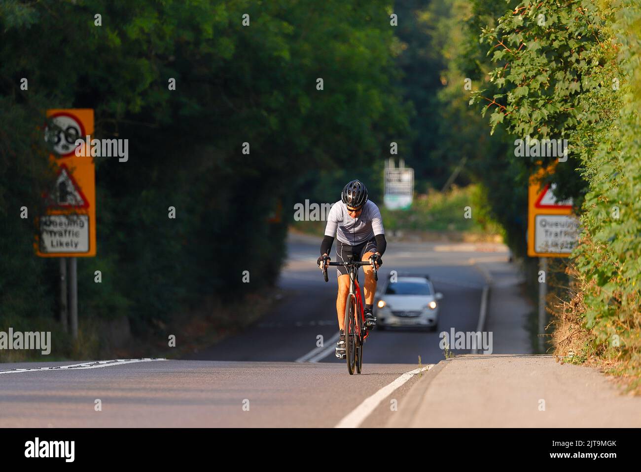 Un ciclista su una strada principale in Swillington, West Yorkshire Foto Stock
