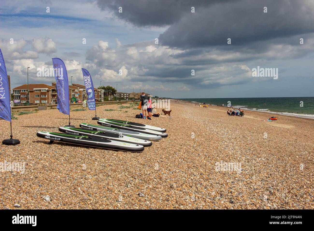 The East Beach, Littlehampton, West Sussex, Regno Unito; mostra la spiaggia, un cafe' e centro per sport acquatici, con tavole da pagaia sulla spiaggia Foto Stock