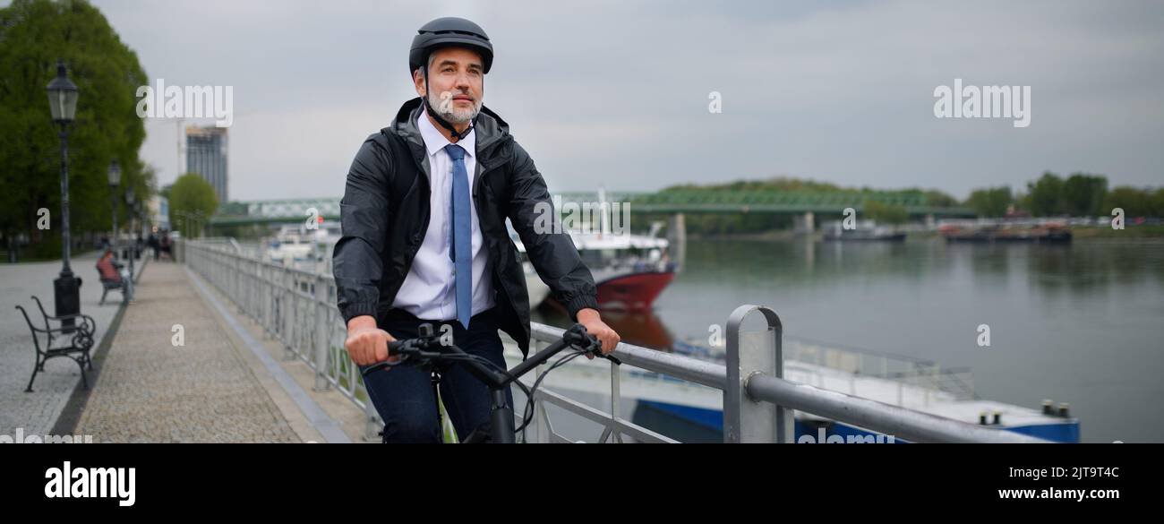 Uomo d'affari che viaggia per lavoro, in bicicletta in città, concetto di stile di vita sostenibile. Foto Stock