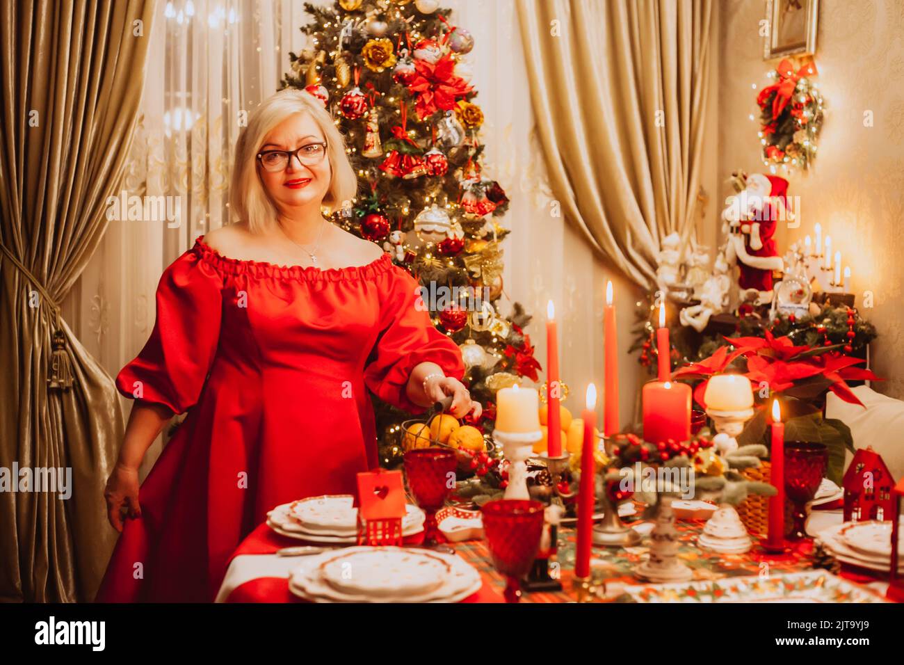 Natale servire a casa. Una donna adulta in un vestito rosso fa un Natale servire a casa. Foto Stock