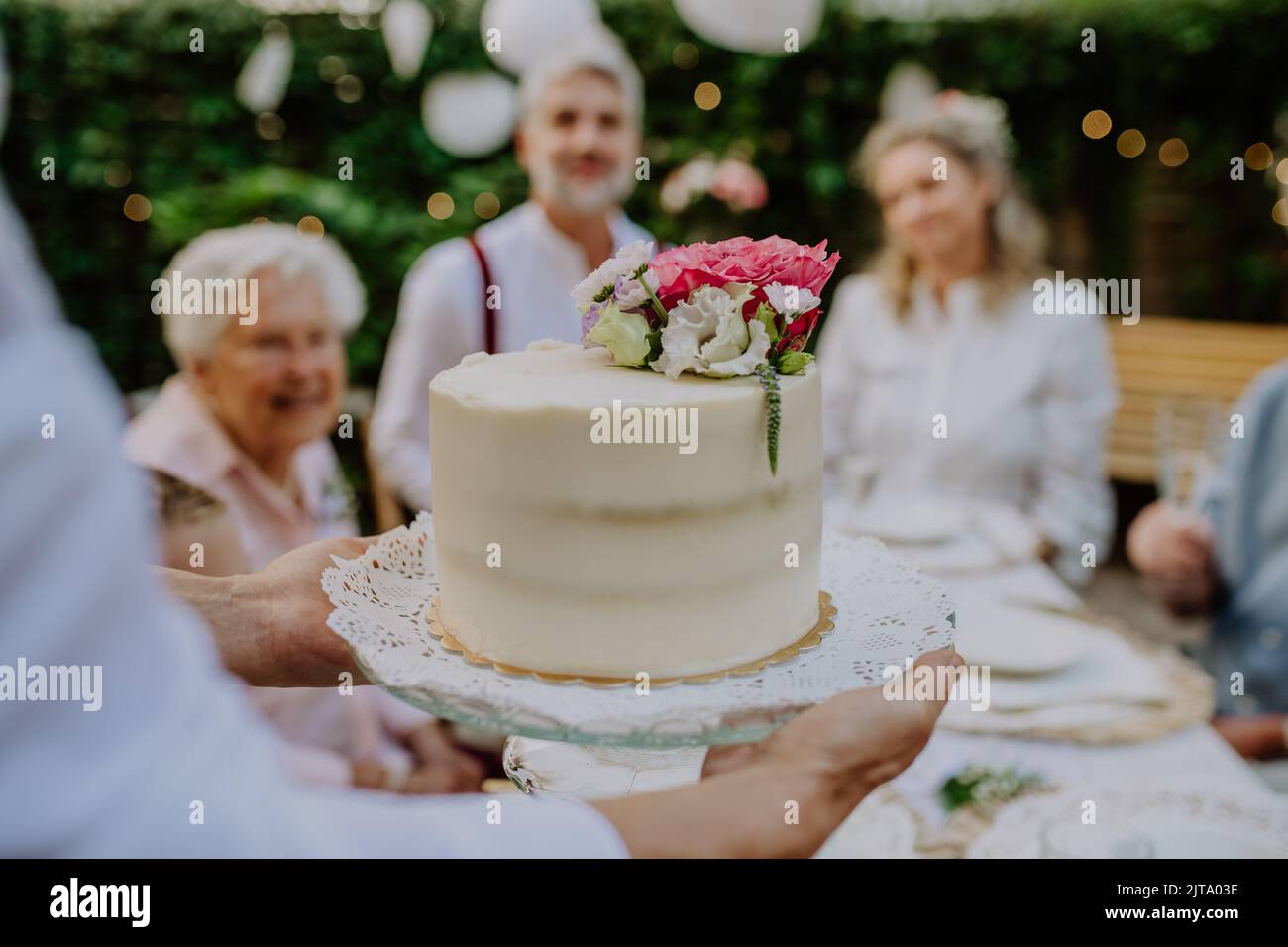 Sposa matura e sposo ottenere una torta al ricevimento di nozze all'esterno nel cortile. Foto Stock