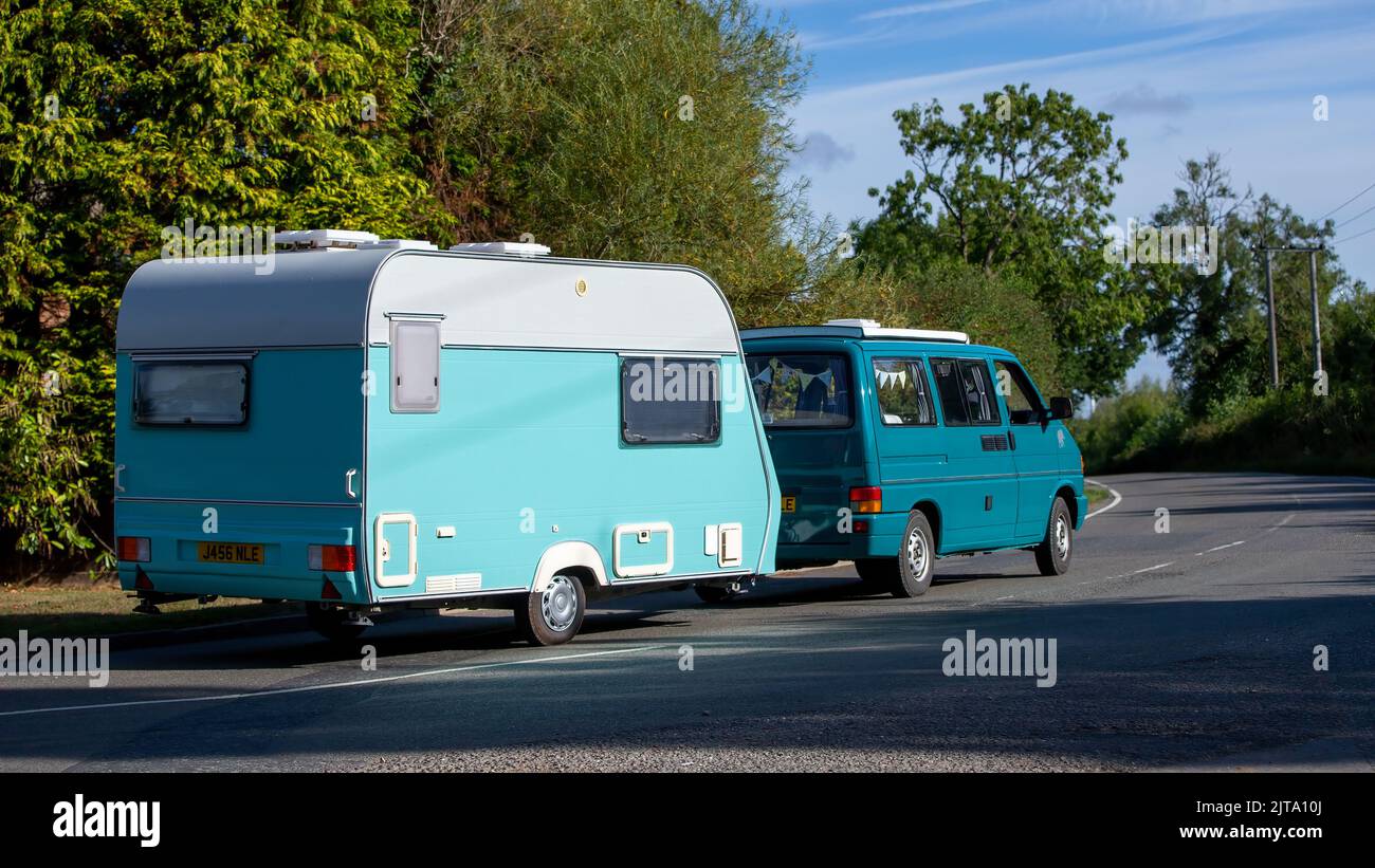 1992 camper Ford che traina una vecchia roulotte su una strada di campagna britannica Foto Stock