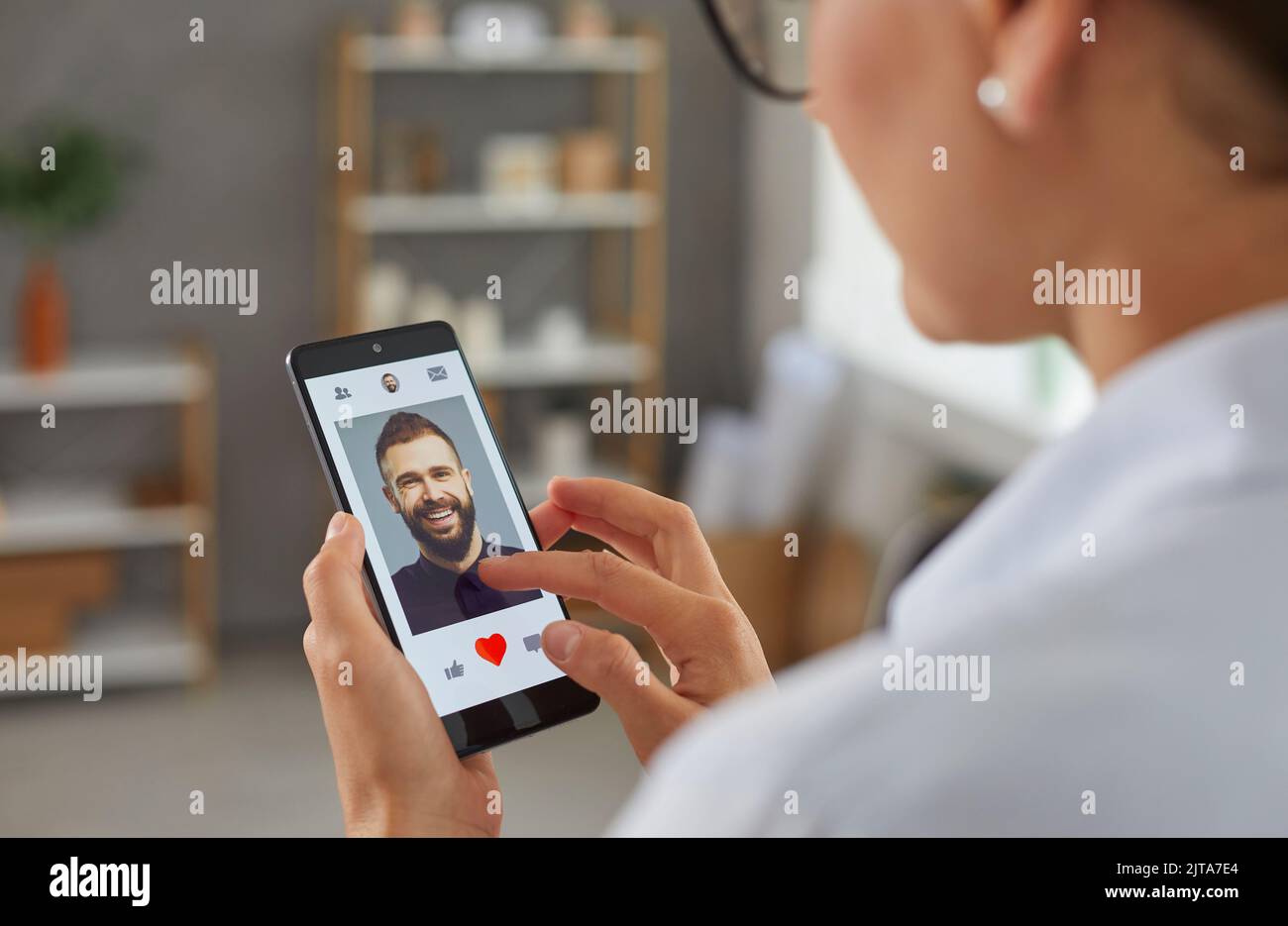 Donna sta andando dare un come a foto dell'uomo in app mobile dating su smartphone. Foto Stock