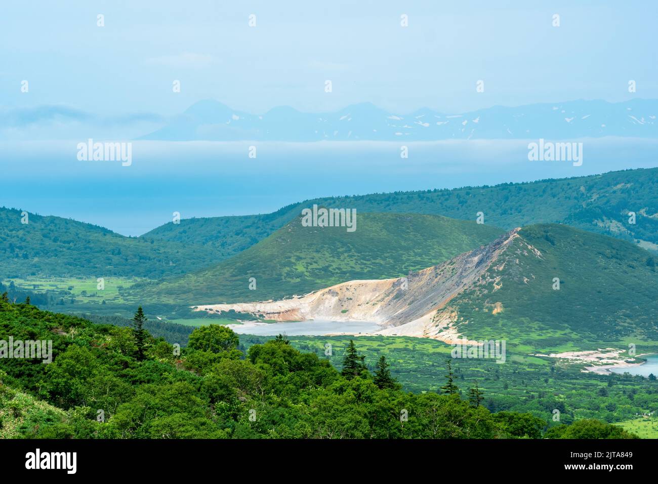 Paesaggio dell'Isola di Kunashir, laghi geotermici tra cupole laviche nel centro del vulcano Golovnin caldera; l'isola di Hokkaido è visibile nel di Foto Stock