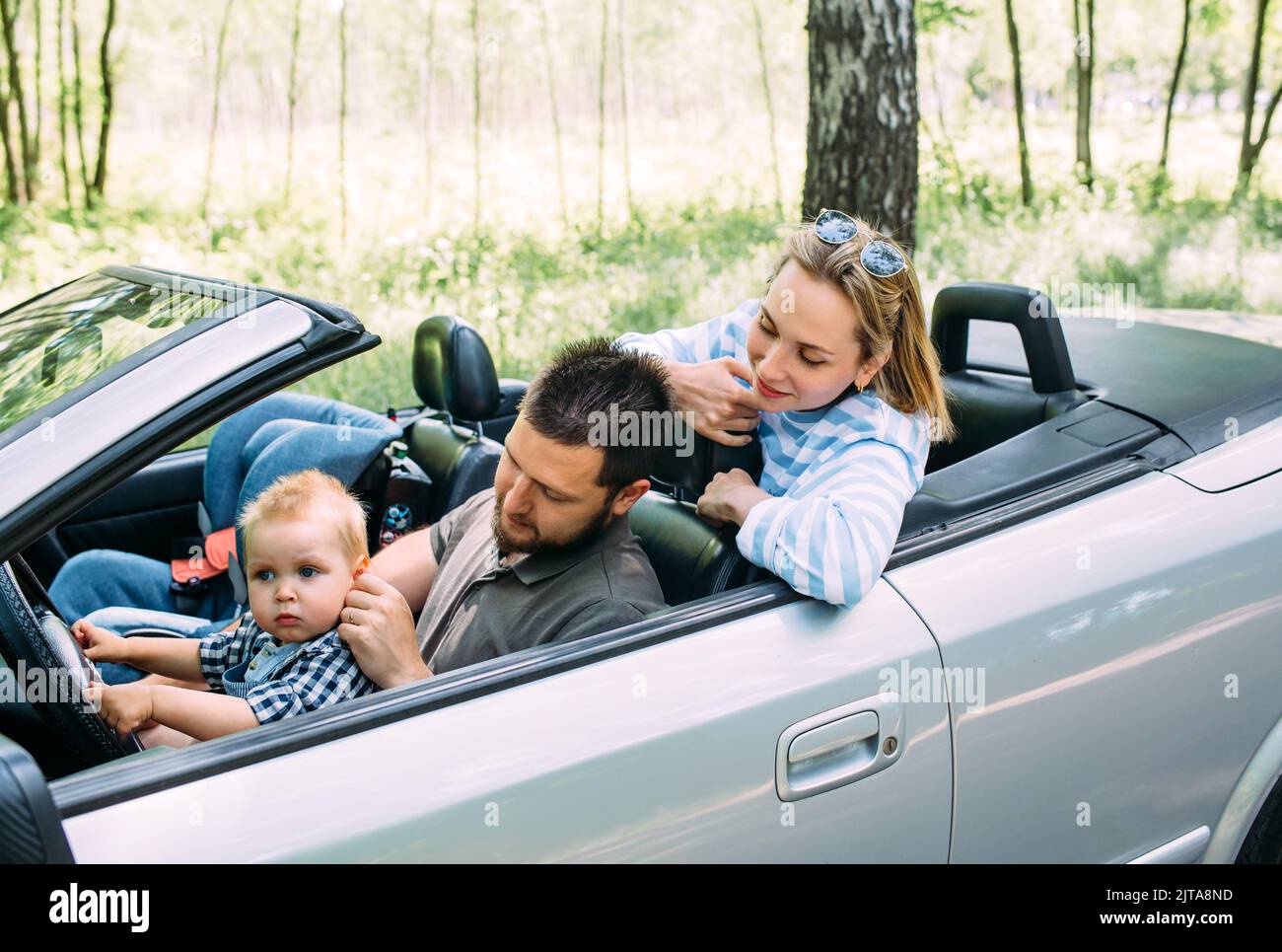 Mamma, papà e figlio piccolo in un'auto convertibile. Viaggio estivo in famiglia nella natura Foto Stock