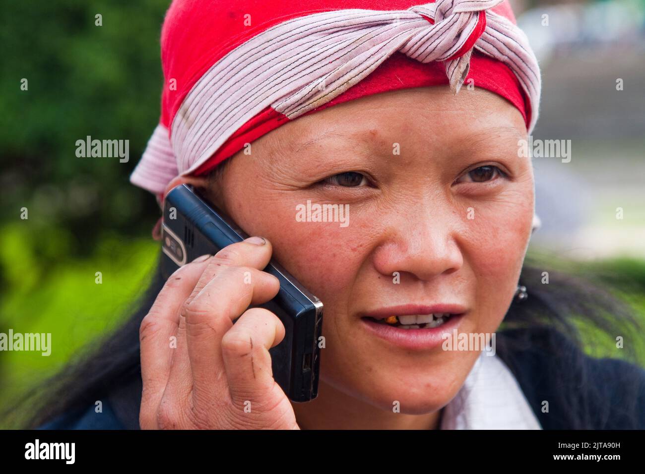 Vietnam, la tribù Red Dao donna sta utilizzando il suo telefono cellulare nella città settentrionale Sapa. Foto Stock