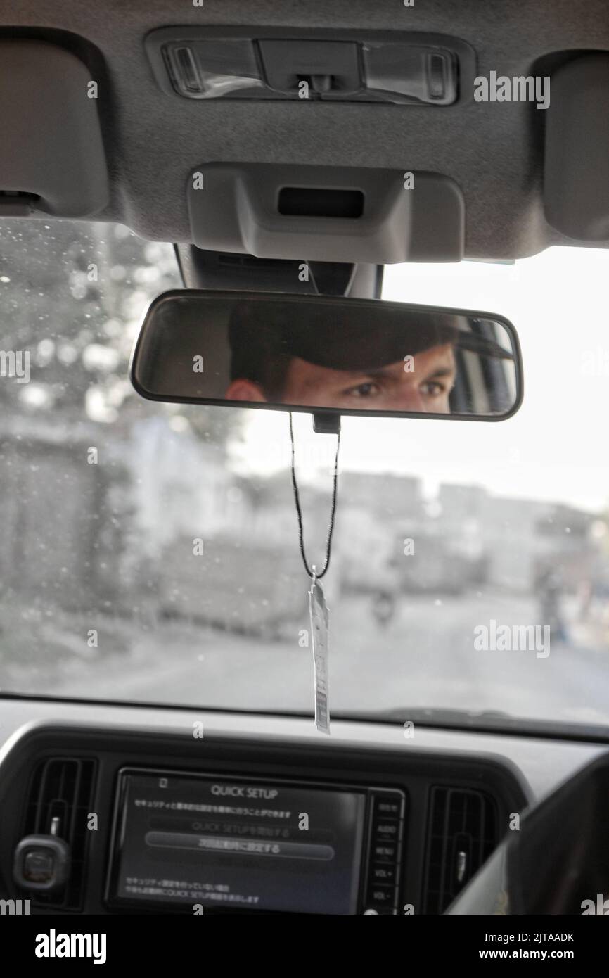 Uomo che guida un viso auto nello specchietto anteriore Foto Stock