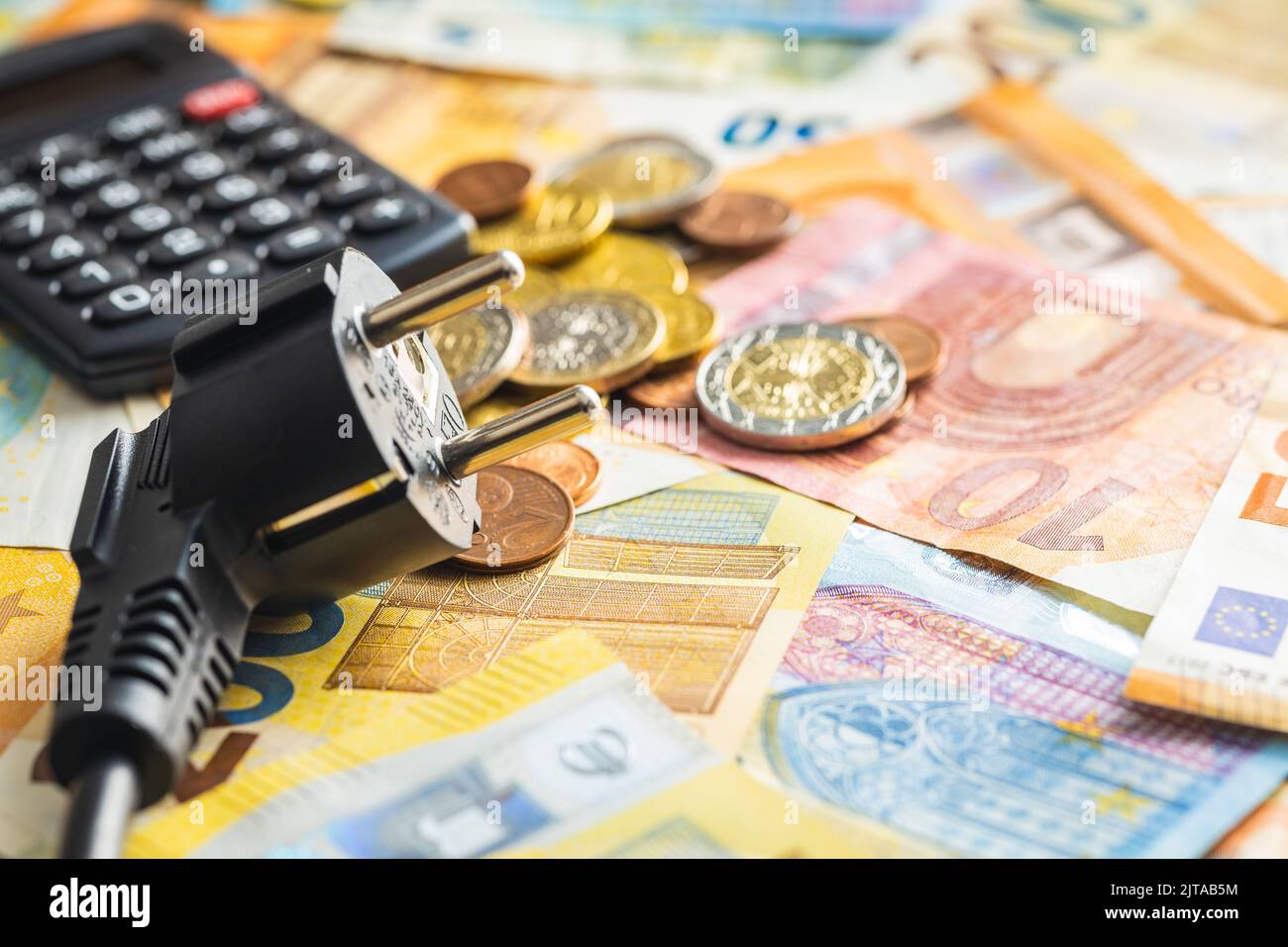 Spina elettrica, calcolatrice e moneta in euro. Concetto dell'aumento dei prezzi dell'elettricità. Foto Stock