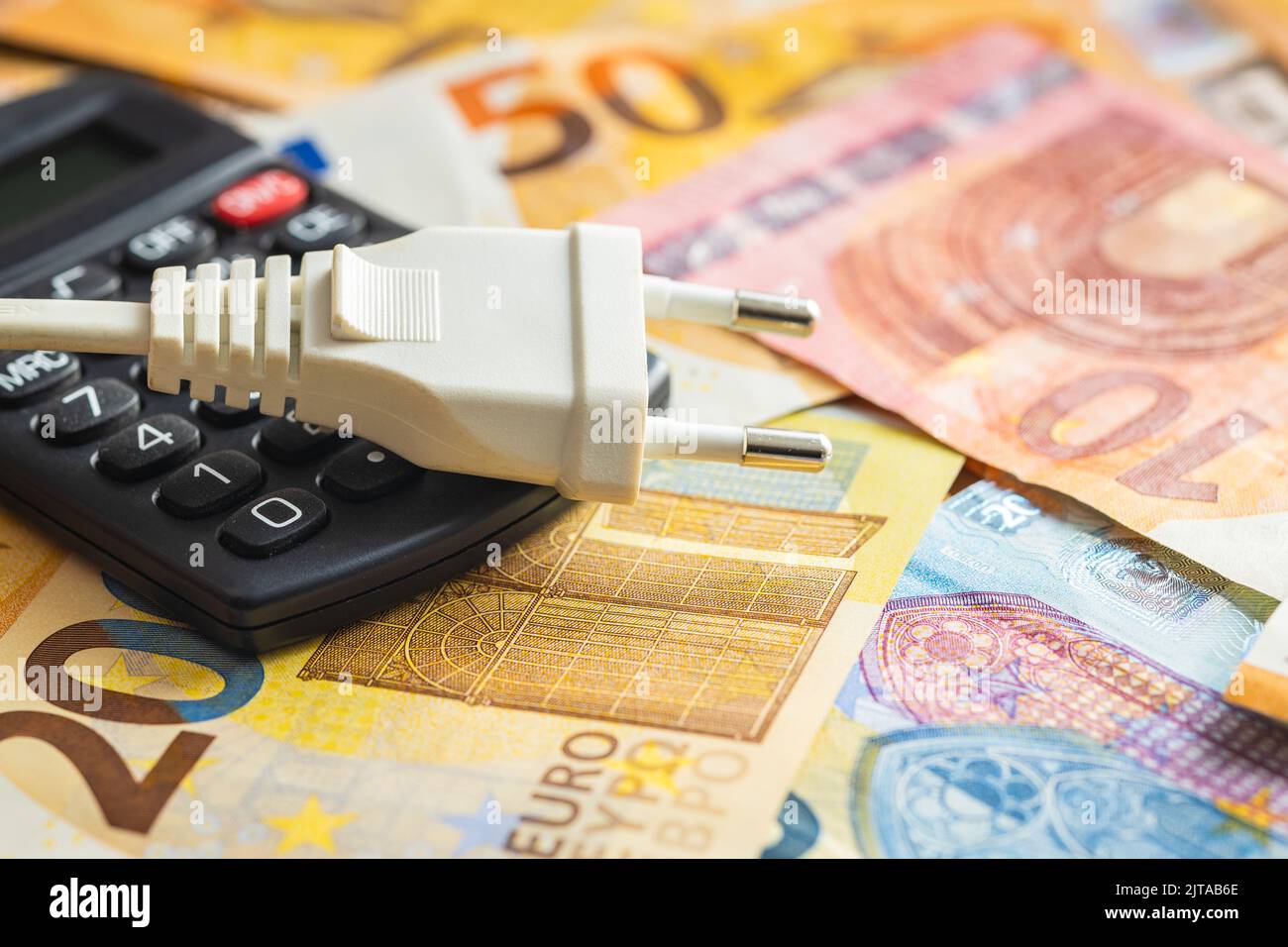 Spina elettrica, calcolatrice e moneta in euro. Concetto dell'aumento dei prezzi dell'elettricità. Foto Stock