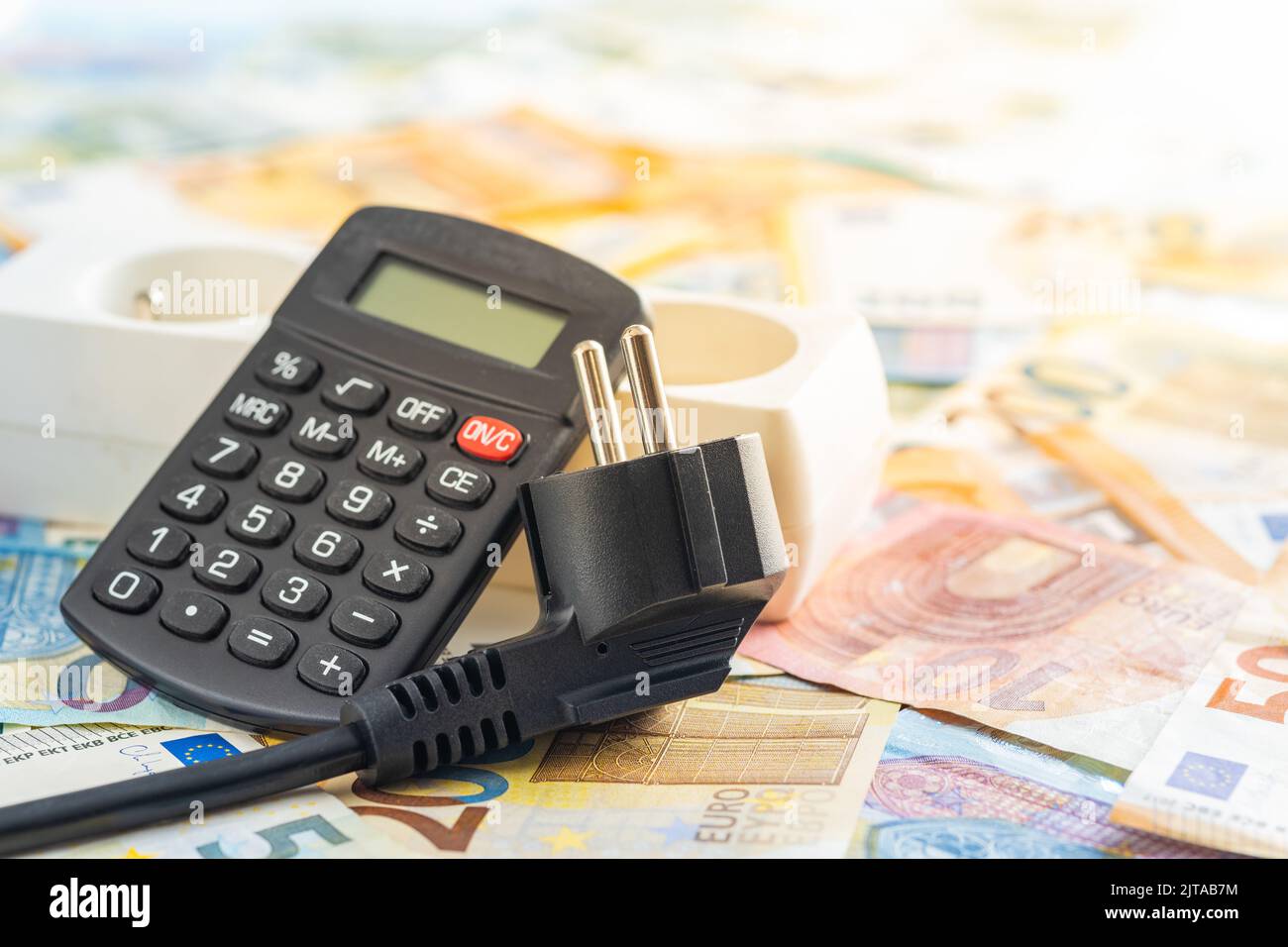 Spina elettrica, calcolatrice e moneta in euro. Concetto dell'aumento dei prezzi dell'elettricità. Foto Stock