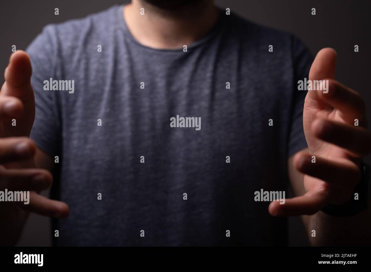 Un primo piano di un uomo in piedi con entrambe le mani sollevate di fronte a lui per presentare qualcosa Foto Stock