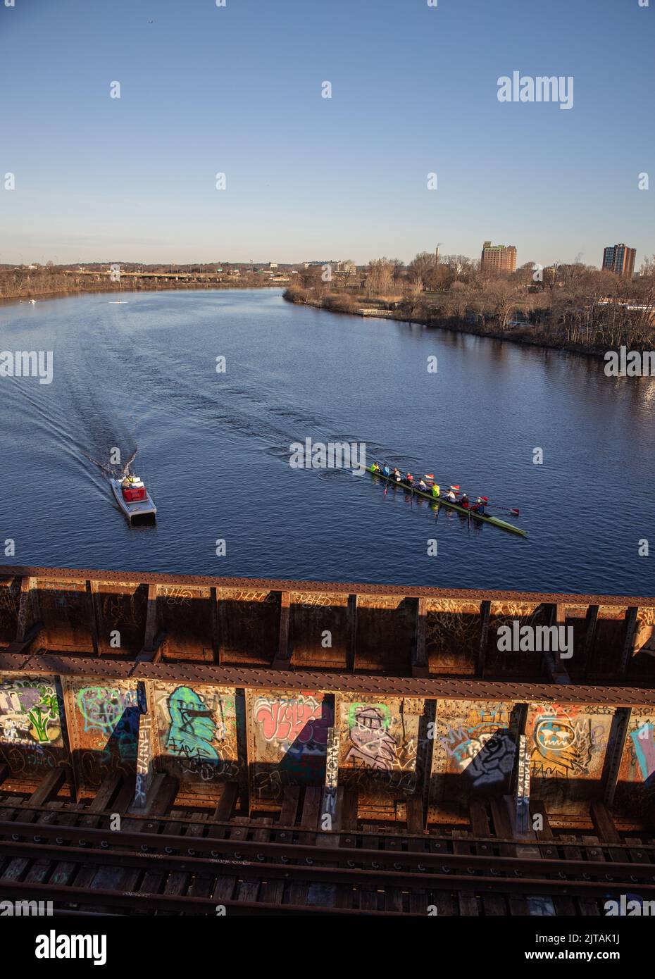 I vogatori che praticano lungo il fiume Charles a Boston si preparano ad andare sotto un ponte ferroviario Foto Stock
