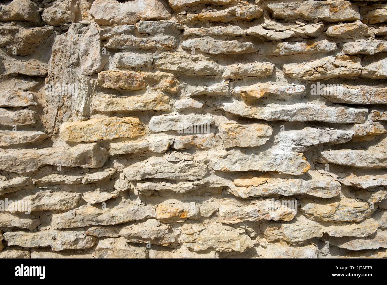 Facciata di un edificio in pietra di pietra naturale con ombre profonde alla luce naturale del sole Foto Stock