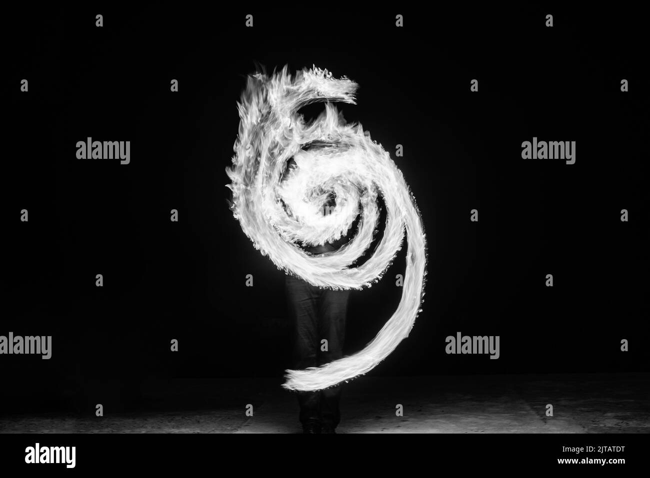 L'artista del fuoco esegue il motivo di archi circolari ardenti di notte in scuro, spirale fibonacci Foto Stock