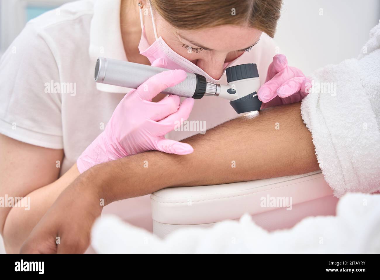 Dermatologo che utilizza il dermatoscopio per l'esame della pelle del paziente Foto Stock