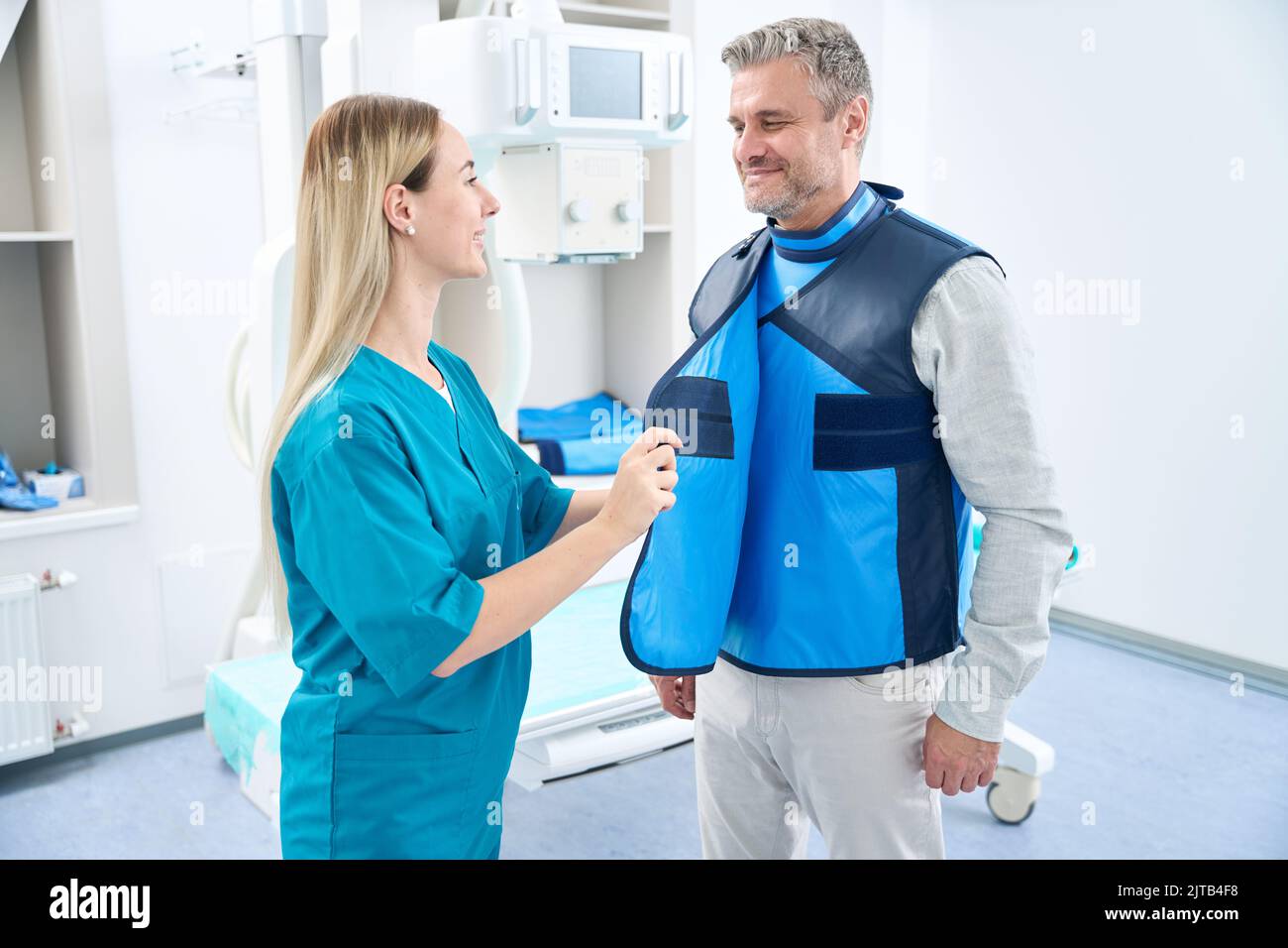 Medico in uniforme blu mette abito protettivo su un uomo Foto Stock