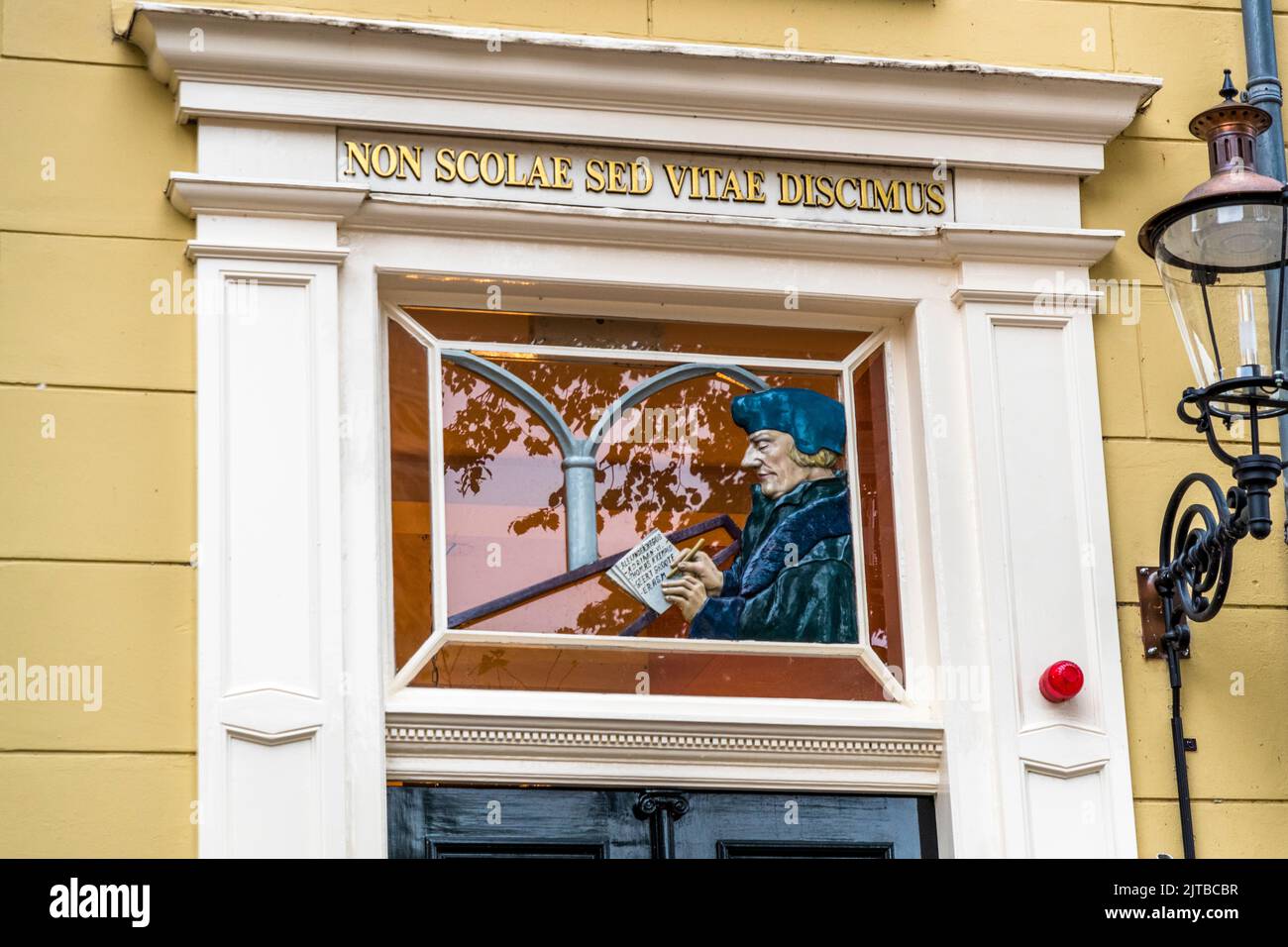 Una raffigurazione dell'umanista Desiderius Erasmus è visibile in una vetrata sopra la porta d'ingresso della storica scuola latina nella piazza Grote Kerkhof a Deventer, una delle nove città anseatiche storiche sul fiume IJssel, provincia di Overijssel, Paesi Bassi. Erasmus frequentò la scuola nella sua gioventù, così come Papa Adriano VI, l'unico papa olandese della storia. È raffigurato mentre tiene un foglio di carta e una penna, sopra di lui il motto "NON SCOLAE SED VITAE DISCIMUS" (impariamo non per la scuola ma per la vita), attribuito al filosofo romano Seneca. Foto Stock